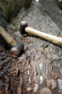 Coins hammered in wood with the hammers that are used next to them.
