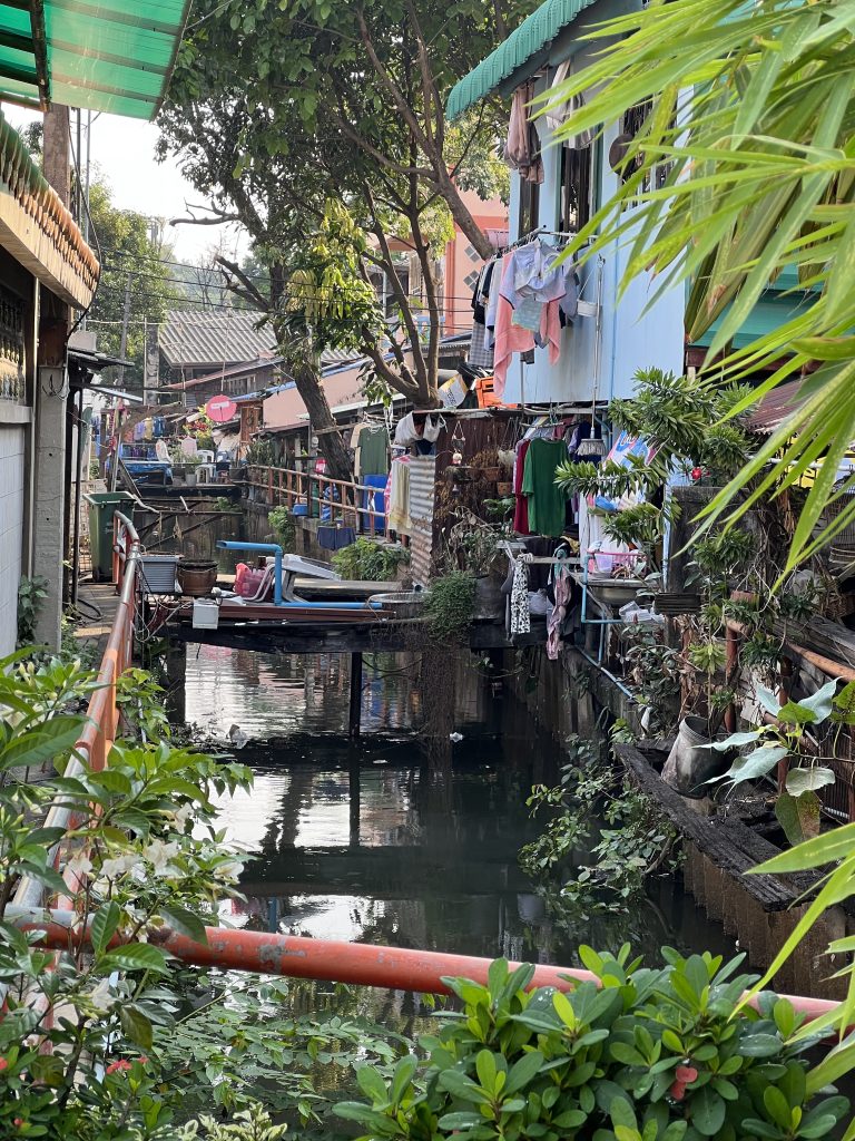 A small stream in Bangkok, Thailand with small apartments and windows overlooking it.