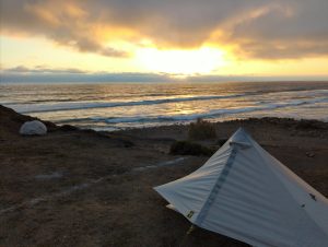 Grey tent pitched on sea cliff at sunset, overlooking the Pacific Ocean, La Misíon, Baja, Mexico.
