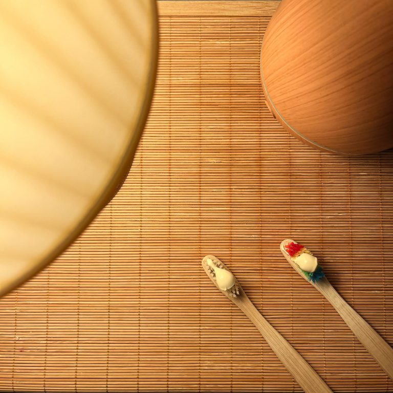 Cozy still life of bamboo toothbrushes with toothpaste on a bamboo mat.