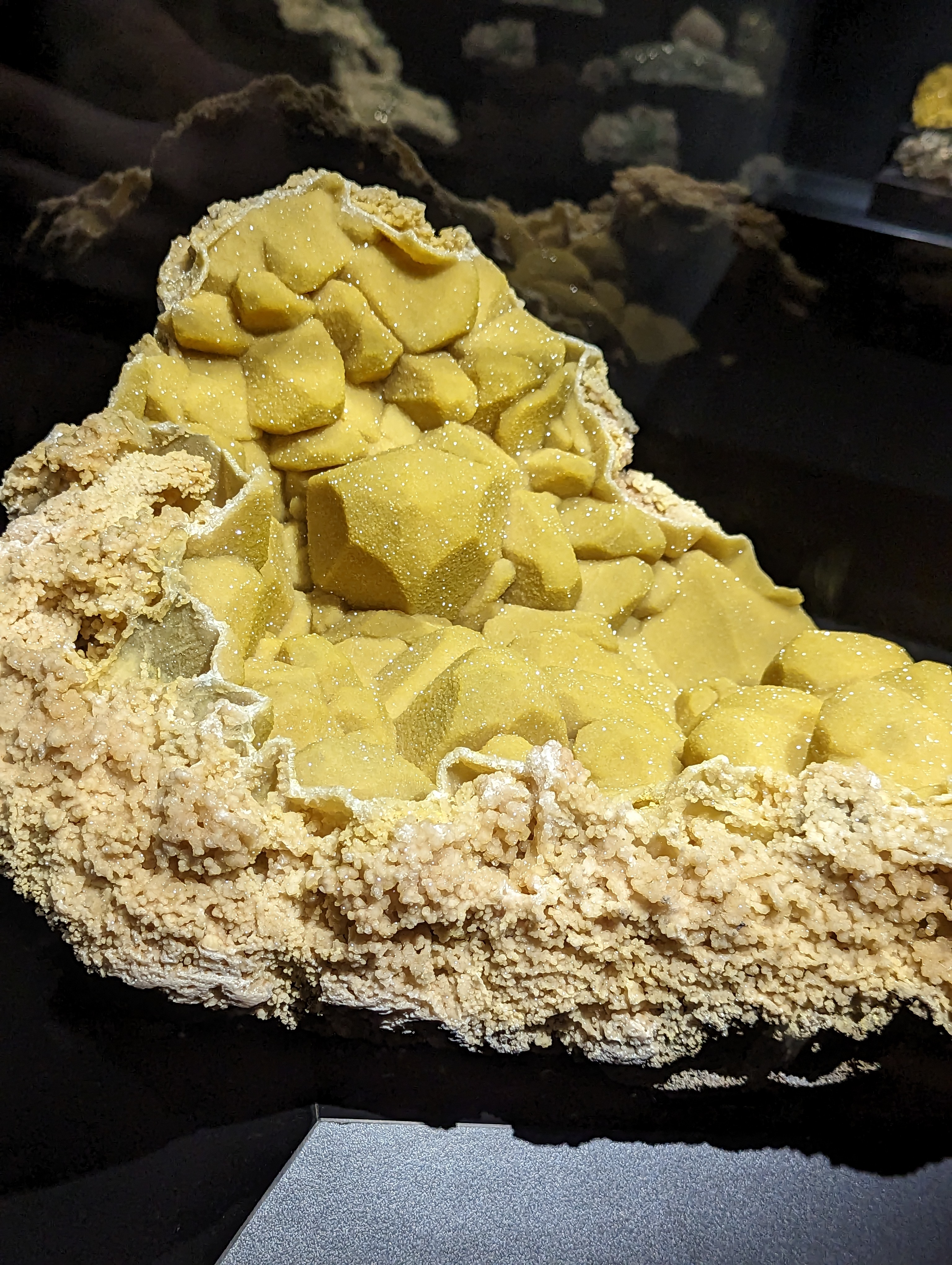 A big bunch of sparkling yellow mineral shapes in a flakey rock.