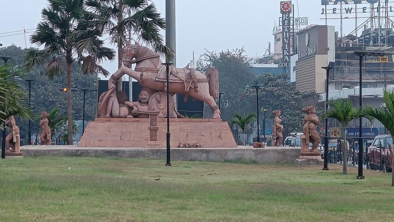 Stone garden statues of a Horse Sculpture inspired by Konark Sun Temple. Giant stone horses in a park, street on the right side.