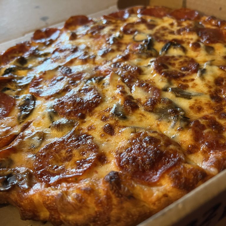 A hot, glistening, cheesy pepperoni and mushroom pizza.