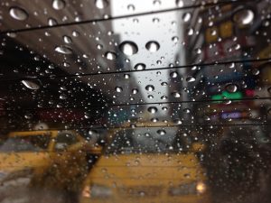 Raindrops on a car window with taxis in the background