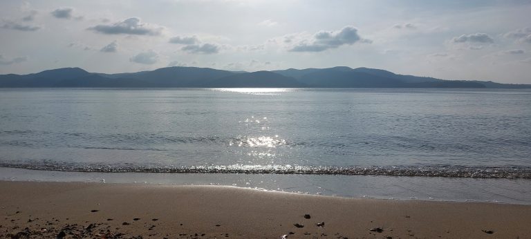 Sandy beach across from some hills.