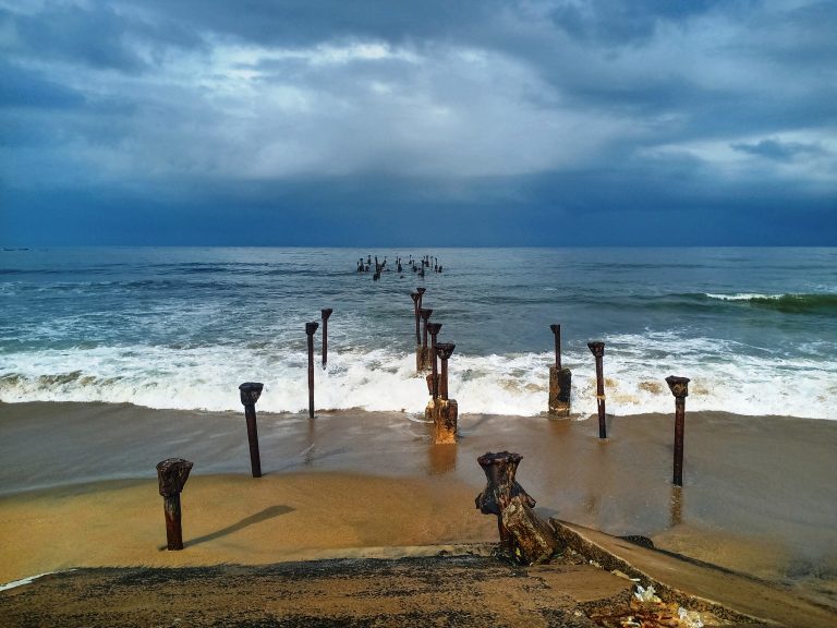 Remaining of an olden sea bridge. It was taken just after a rain. From Kozhikode Beach, Kerala. Only posts remain, leading from the beach into the ocean, waves washing between.