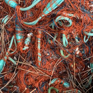 Tangled bundle of fishing nets in teal and orange colours.
