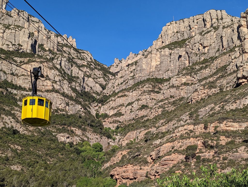 Yellow cable car at Funicular Aeri de Montserrat, Barcelona, Spain, with the Montserrat mountain in the background.