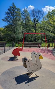 View larger photo: Frog and duck swings on playground, green trees in the background. Spring in park in Gliwice, Poland.