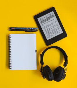 Flatlay de kindle con libreta y audífonos sobre fondo amarillo.

Flatlay of kindle with notebook and headphones on yellow background.