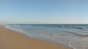 Photo of a beach. Matalascañas (Huelva – Spain).  Sand on the left, light, shallow surf on the right.
