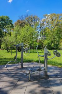 Outdoor gym in park in Gliwice, Poland. Gym equipment, green trees in the background.