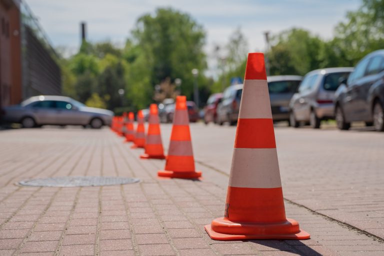 Image shows a car park scene filled with parked vehicles and orange safety cones blocking the remaining spots. It encapsulates urban transportation, parking challenges, and city infrastructure. Ideal for themes around city life and traffic management.