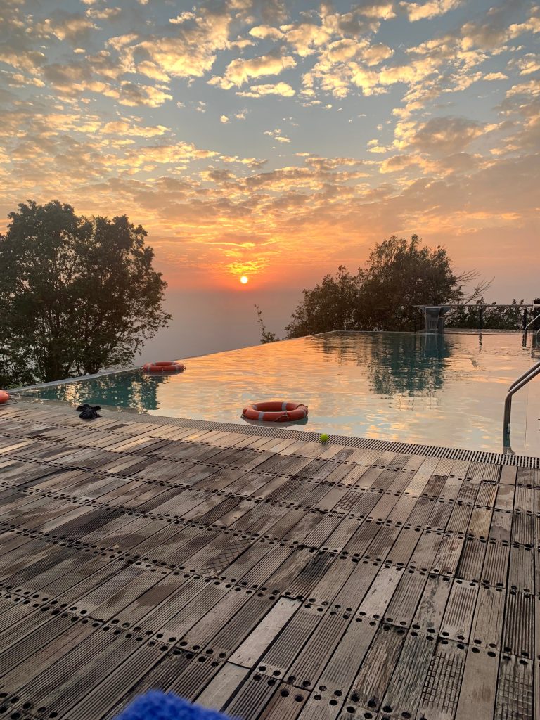 Sunset on a infinity pool of bangladesh. Sairu Hill Resort. Brick patio in the immediate foreground, then the pool, then a long view with the sun setting in the far distance.