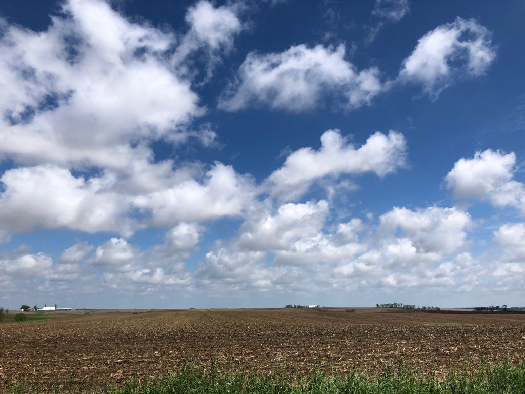 Countryside landscape featuring a blue sky, clouds and unworked farm ground