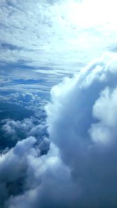 A sky filled with clouds of a variety of type.  The view is from above, from an airplane.
