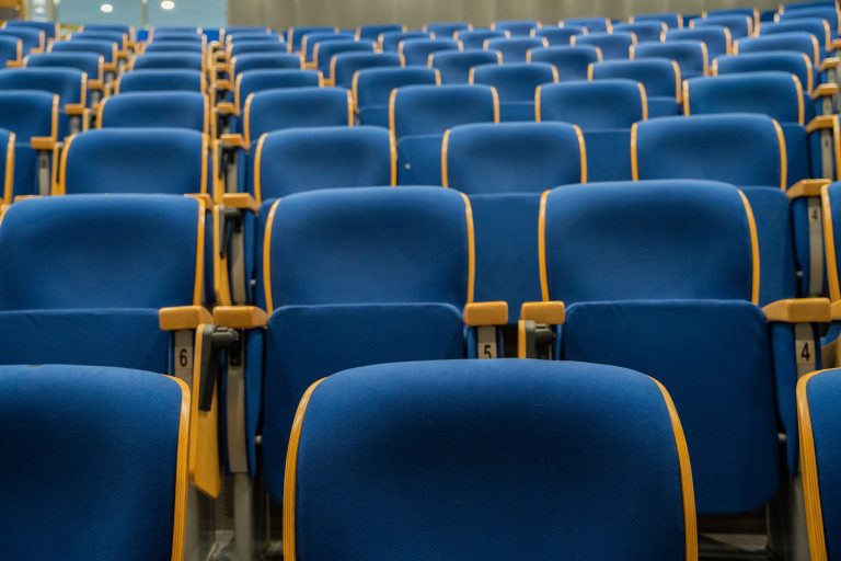 Image of a large, empty auditorium with rows of blue seats. The venue could host concerts, lectures, conferences, or movie screenings. This photo captures the anticipation of a cultural event, performance space, and public gathering. Ideal for event and venue themes.