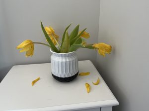 A nightstand with a vase holding slightly wilted tulips.