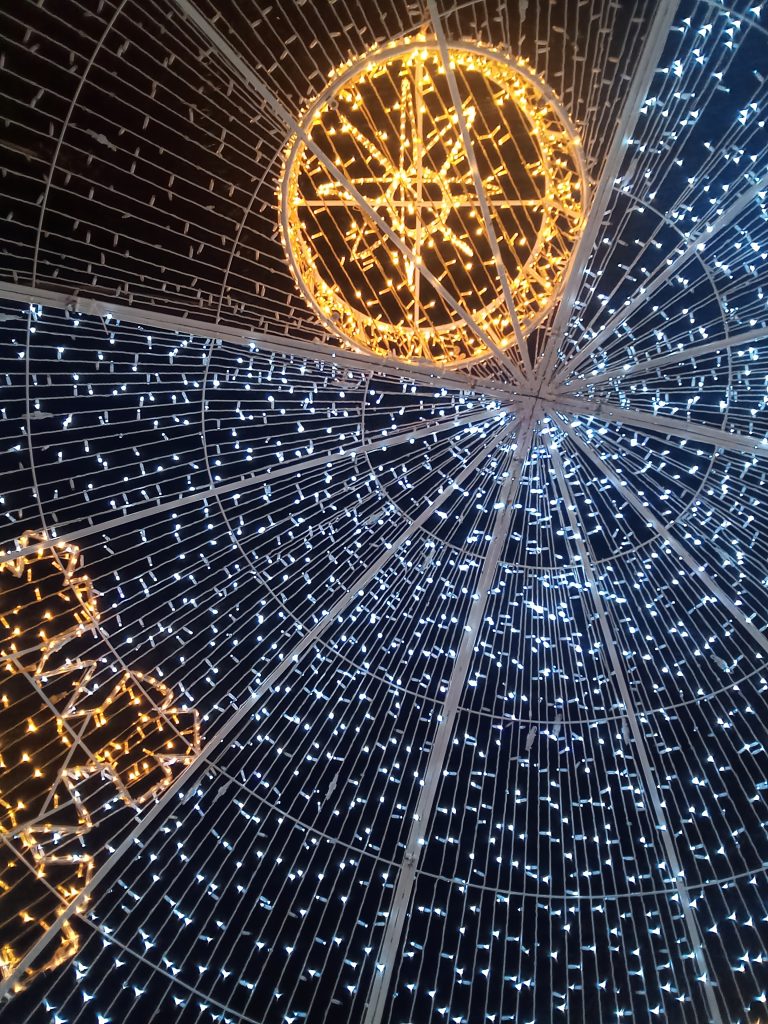A Christmas tree made of small lights seen from below