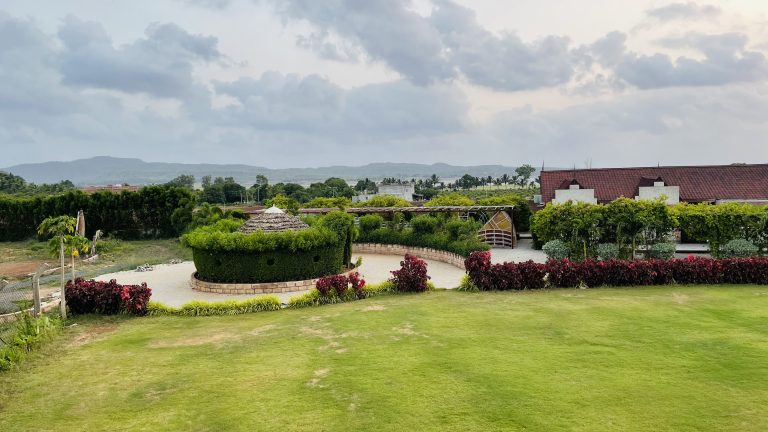 View across a lawn of a resort. Large circular feature in the center, like for driving around. Long view has mountains on the horizon.