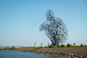 View larger photo: A 26 meter high statue of a crouching man, created by artist Antony Gormley on the banks of the Markermeer, near Lelystad, The Netherlands.