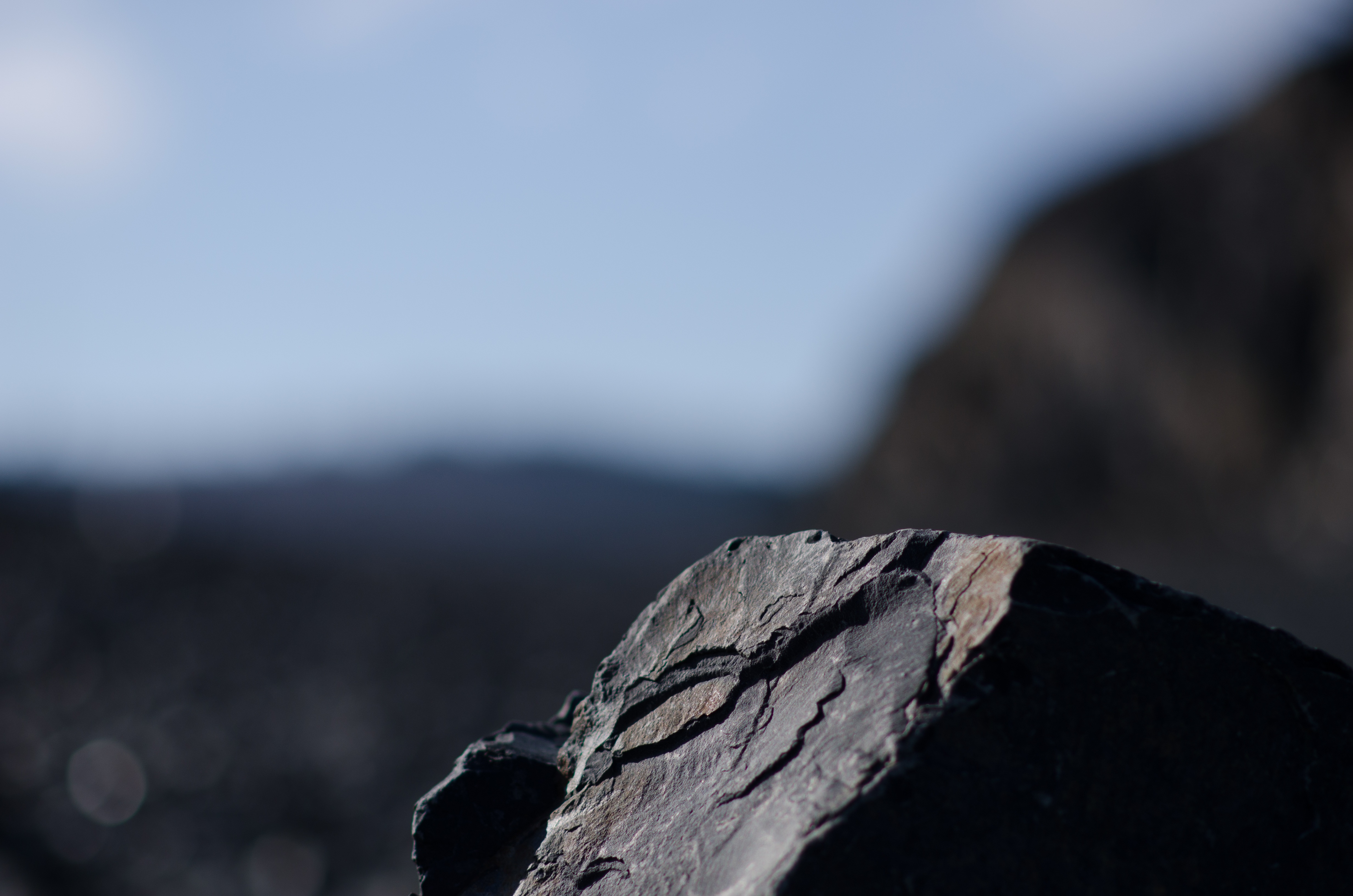 A dark black rock against a blue sky.