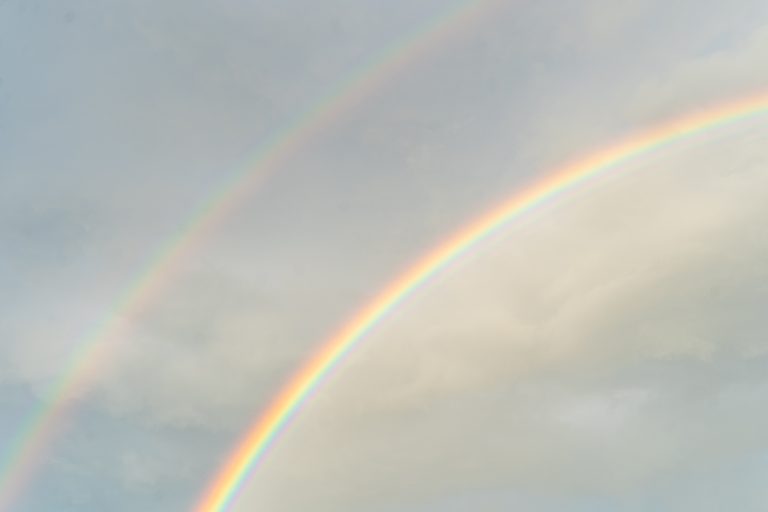 A double rainbow over a blue sky.