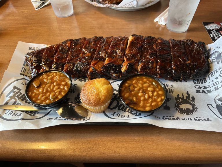 A whole slab of ribs, two bowls of beans, and a cornbread muffin.