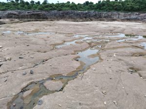 Mostly dry river bed with scattered pebbles.