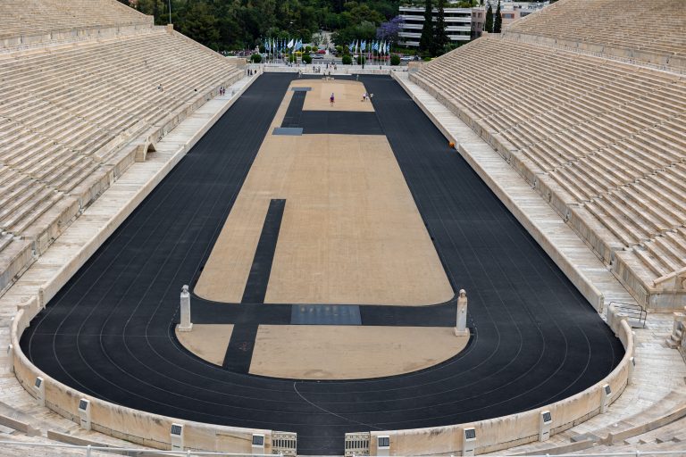 The original olympic stadium in Athens, Greece with the track in the center and stone bleachers on the left and the right