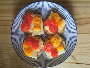 View larger photo: Seasoned tomato slices on cheese on crackers.  Four crackers arranged on a plate.