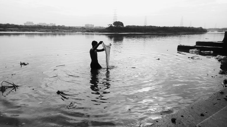 A person washing the clothes in the Yamuna River