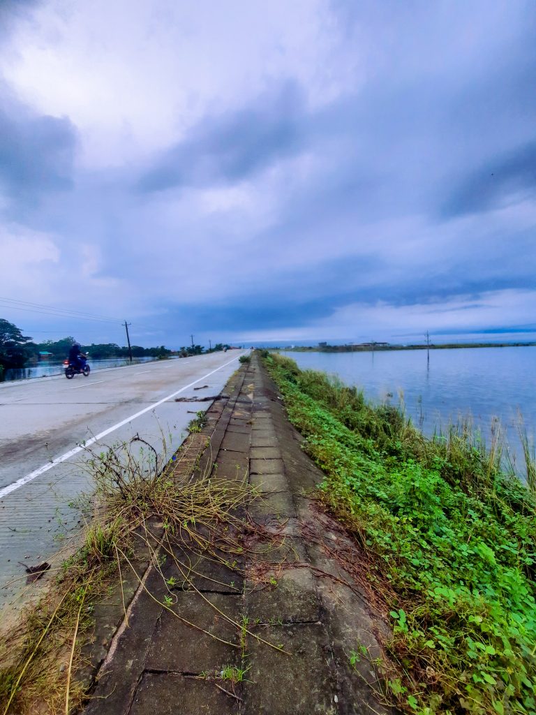 Empty road beside the river with very moody sky and clouds.