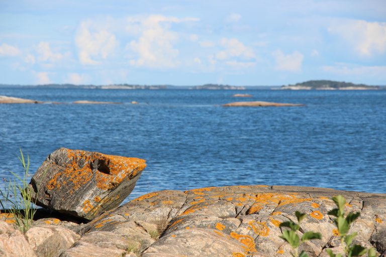 Cliffs in the archipelago of ?land with stones coverd in lichen in the front and the sea (blurred) in the back