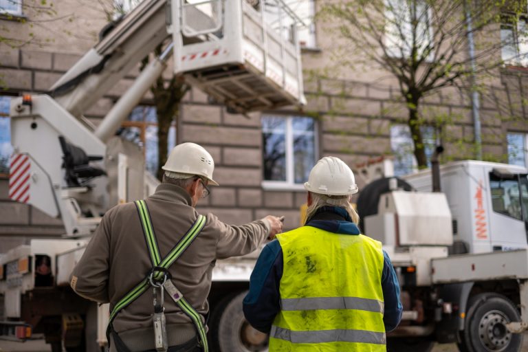 Construction workers standing in front of a big work truck.