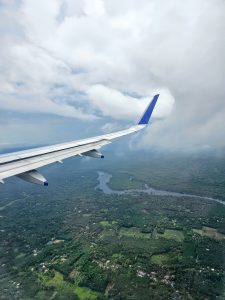 View of cloudy sky and and landscape with river through airplane window. 