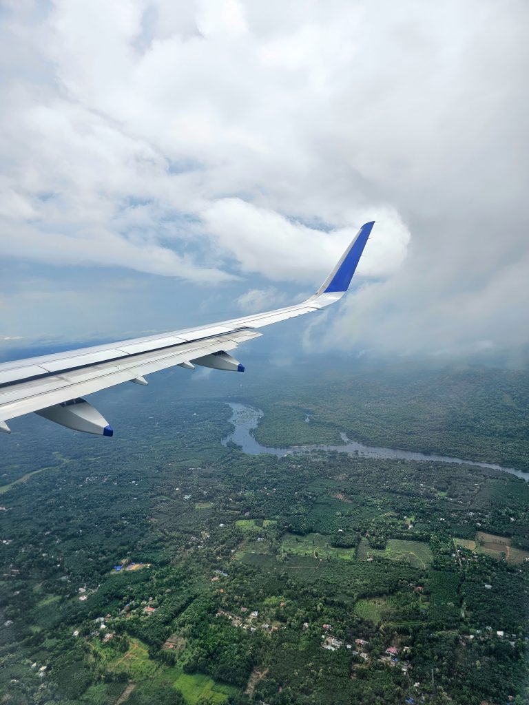 View of cloudy sky and and landscape with river through airplane window.