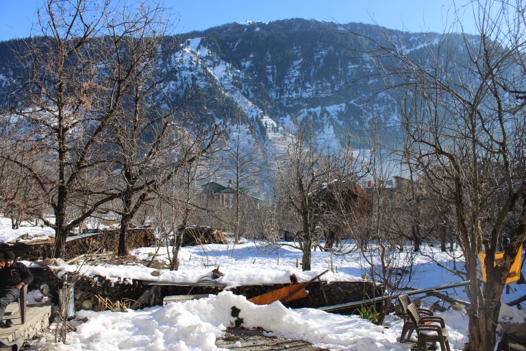 High altitude: A view of a snowy ground with a house and a mountain in the background.