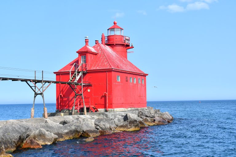 The red Sturgeon Bay Ship Canal Pierhead Lighthouse, is a historical landmark located on Lake Michigan and viewable from the Sturgeon Bay United States Coast Guard Station.