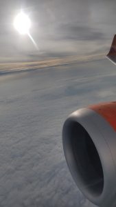 View from the aeroplane, 30,000 feet from the ground level in the midst of the flight.  Engine in view, cloud deck far below.
