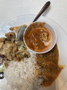 A plate fulled with food. There is rice, chicken curry and some chhat in the plate.