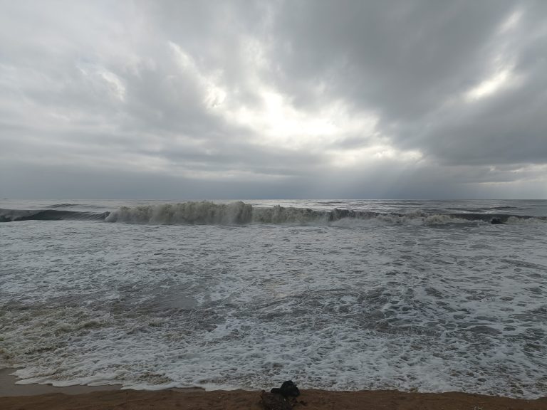 Rolling surf coming up onto a beach. Very cloudy sky so the sky an water are very similar in color.