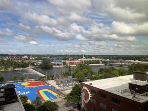 Grand Rapids MI, partly cloudy sky, the Grand River in the center, brightly painted parking lot in foreground.