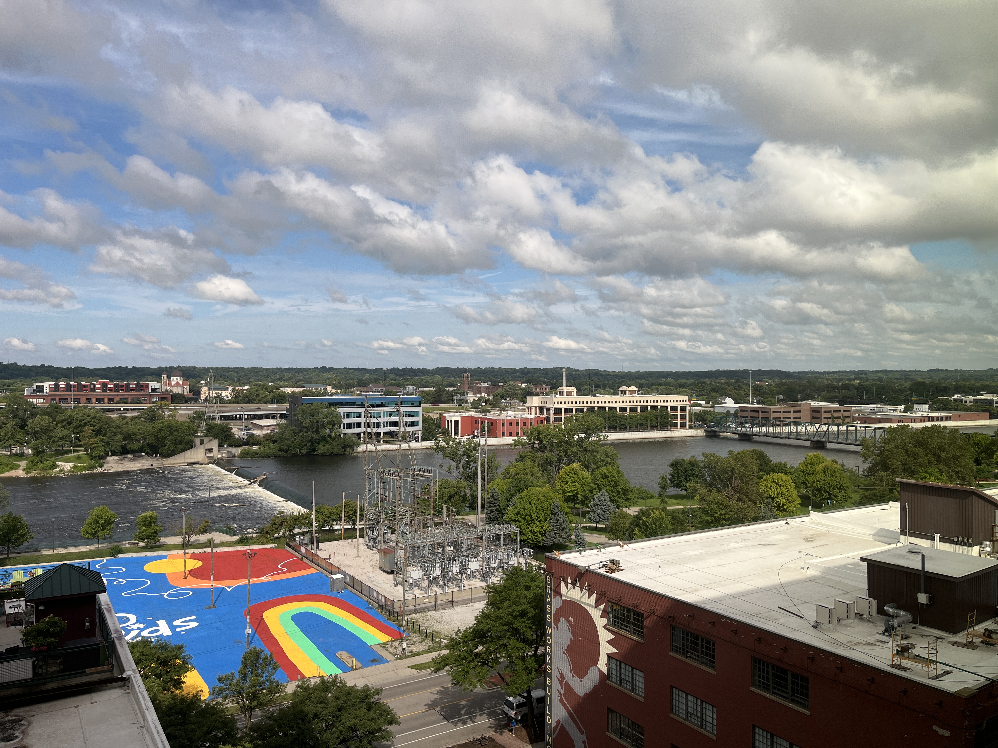 Grand Rapids MI, partly cloudy sky, the Grand River in the center, brightly painted parking lot in foreground.