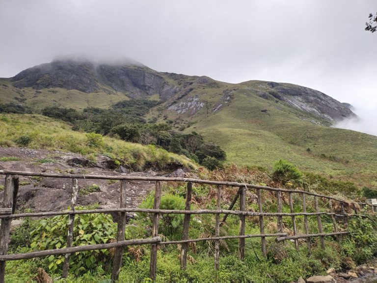 A greenery sand rock hill covered by clouds in Rajamala, Munnar.