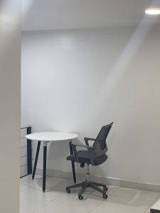 An unoccupied table and chair in a quiet co-working space with light streak from the ceiling light to the table
