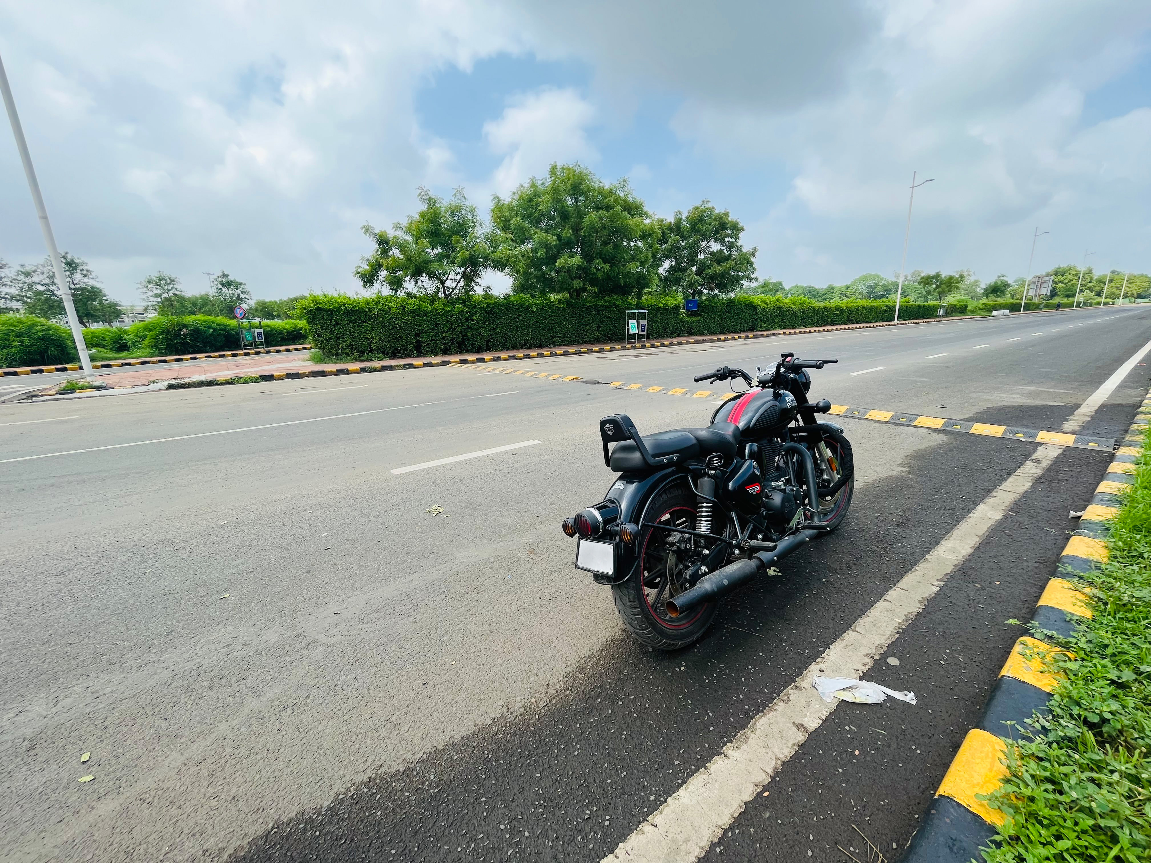 Royal Enfield motor cycle parked on the side of wet road. 