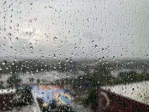 Raindrops on a window with a blurry background of a view of a city from inside