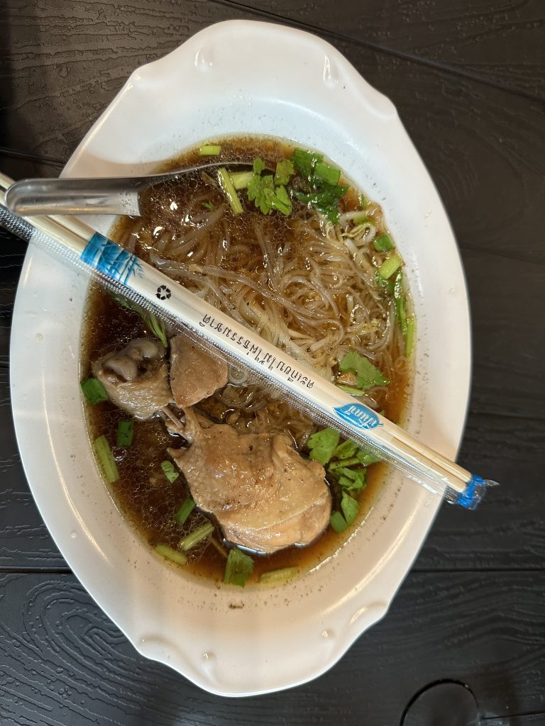 Thai food with chicken, noodles and chopsticks.