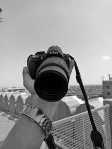 A Nikon camera in the hand of a person. Black & white image.
